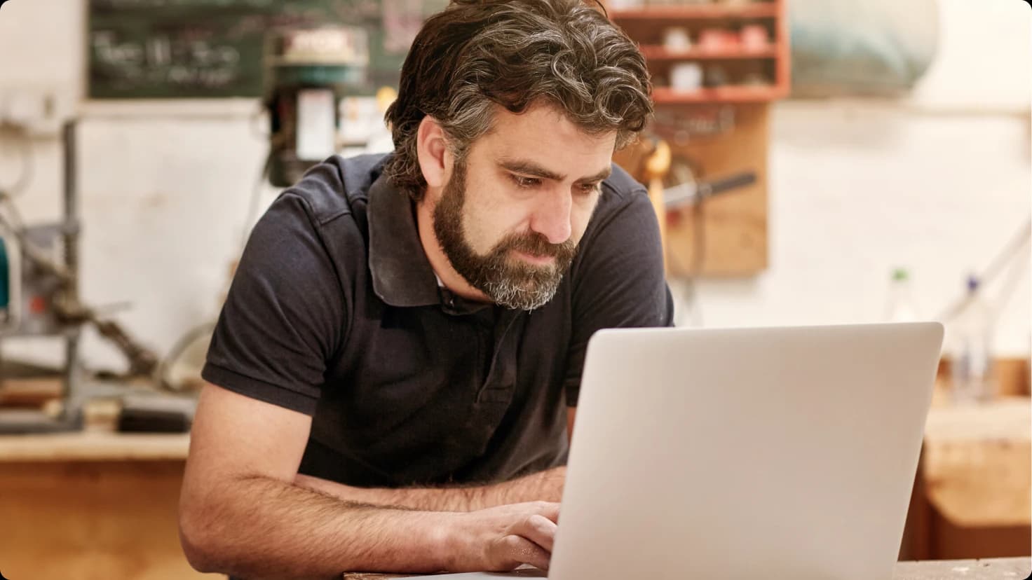 Male Working On His Laptop In Workshop