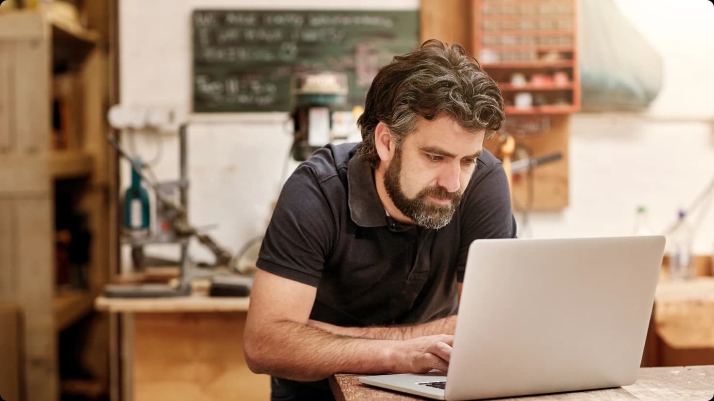 Male Working On His Laptop In Workshop