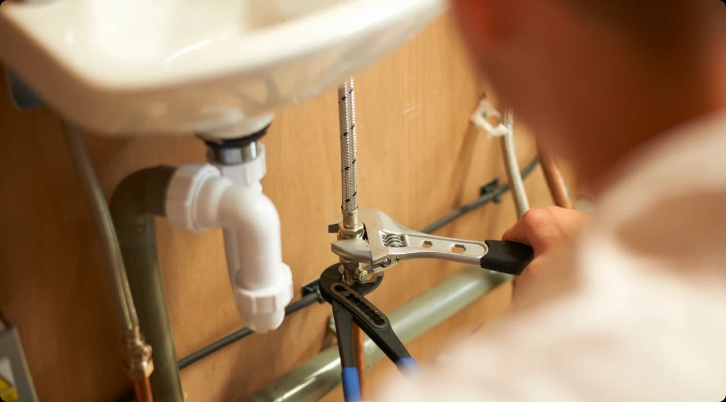 Close Up Plumber Repairing Sink Pipes With Wrench
